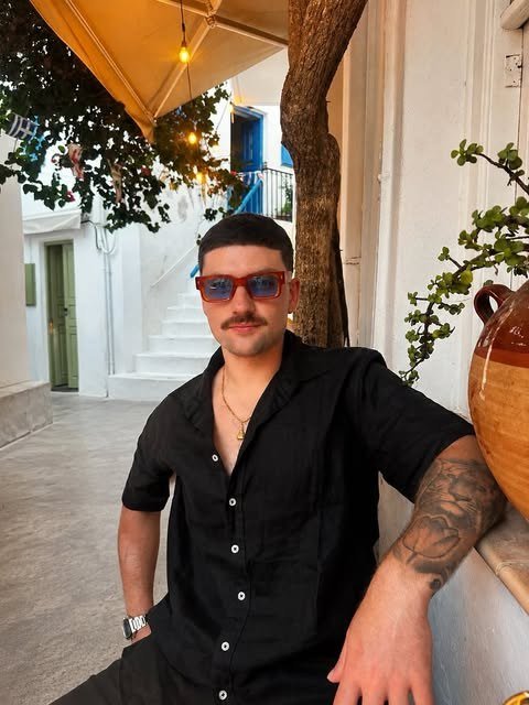 B.Y., an Austin DJ, in a black shirt and red sunglasses on a whitewashed street.